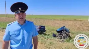 Позади сотрудника видны обломки автомобиля.